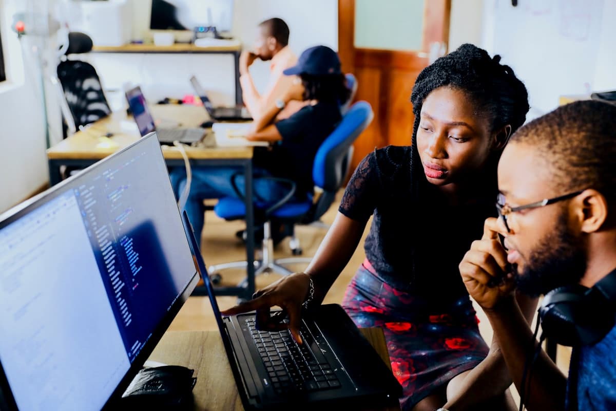 Two colleagues working together at a computer in a small business office